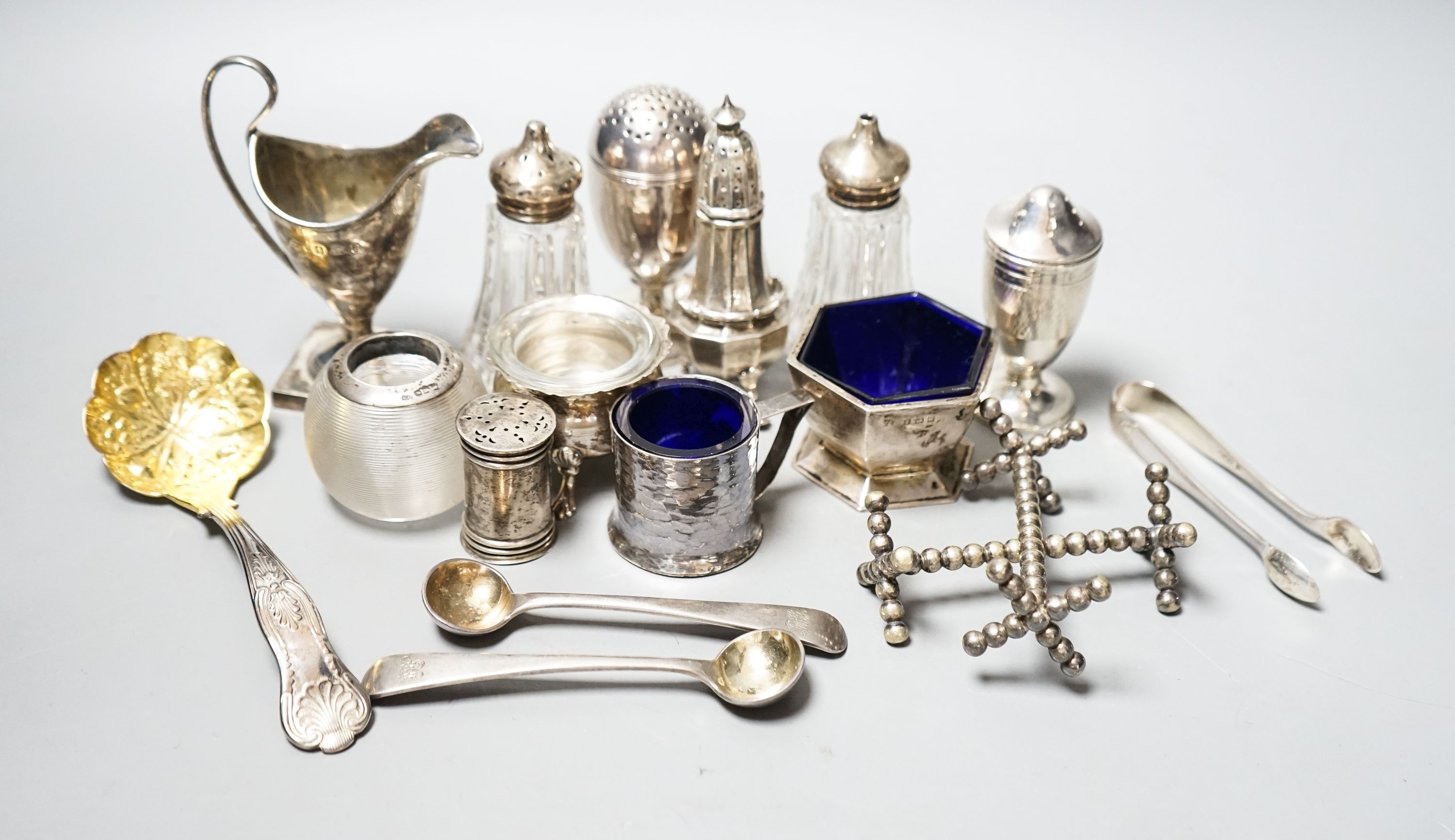 A group of small silver including condiments, match strike, cream jug, plated knife rests etc.